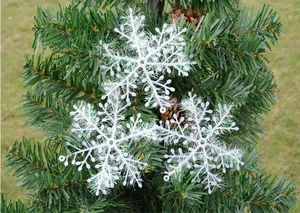 Gedetailleerd overzicht van drie witte glitterende sneeuwvlokornamenten aan een groene kerstboom