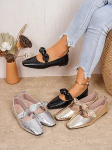 Detailed shot of Mary Jane flats with bow tie in black, silver, and gold metallic