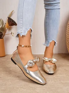 Champagne gold metallic Mary Jane flats with a stylish bow decoration worn with denim jeans