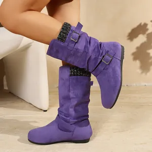 Dettaglio degli stivali a metà polpaccio in camoscio viola con fibbie e polsini in maglia.