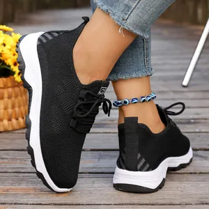 Close-up view of breathable black mesh walking shoes with white soft soles on wooden deck.