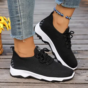 Detail view of breathable black mesh walking sneakers with white sole on model feet