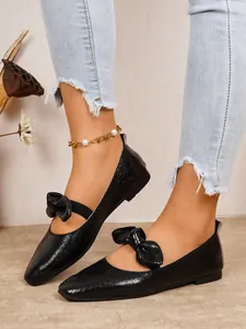 Detail view of stylish black Mary Jane flats with bow decoration worn with jeans