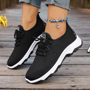 Detail view of breathable black mesh walking sneakers with white soft soles on boardwalk