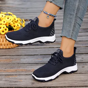 Detailed view of breathable navy blue mesh walking sneakers worn on a rustic wooden deck.