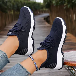 Detail view of breathable navy mesh walking shoes with soft white soles worn outdoors.
