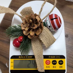 Detail shot showing the 24g weight of a rustic Christmas pine cone and bell ornament.