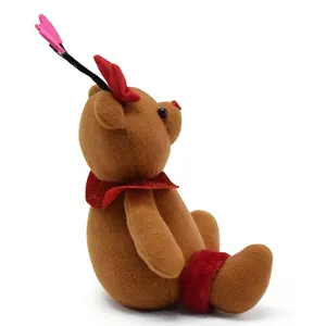Side profile of a cute brown plush bear ornament with red bow and pink heart decor