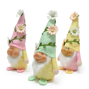 Primer plano de tres gnomos primaverales con sombreros de flores y caras de resina.