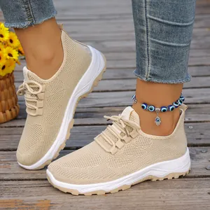 Close-up of breathable beige mesh walking sneakers with white soft soles on a wooden deck