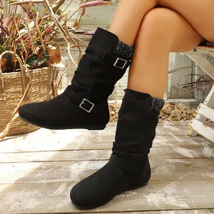 Primo piano di stivali slouch in camoscio nero con fibbie decorative e collo in maglia