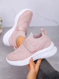 Detail van roze sneakers met strass, dikke witte zool en gebreid ademend bovenwerk.