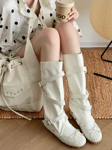 Detailed shot of white ballet-style boots with detachable buckle straps and bow