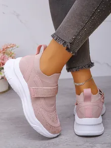 Detailopname van roze strass-sneakers met klittenbandsluiting en dikke witte platformzolen.