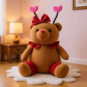 Close-up detail of handmade brown teddy bear plush with red bow and pink heart antenna