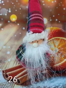 Macro view of a cute plush Christmas gnome doll with plaid hat resting on cinnamon sticks
