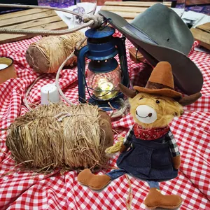 Detail view of a cute plush highland cow dressed in cowboy attire on a farm scene.