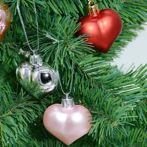Primer plano de adornos de corazones metálicos colgados en un árbol de Navidad