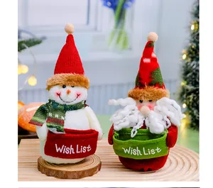 Detailed view of plush Santa and snowman dolls holding green and red Wish List bags