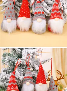 Detailed view of knitted Nordic Christmas gnomes hanging as ornaments on a snowy tree