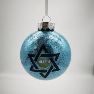 Nahaufnahme einer blau glitzernden Hanukkah-Kugel mit Davidstern und Menora-Motiv.