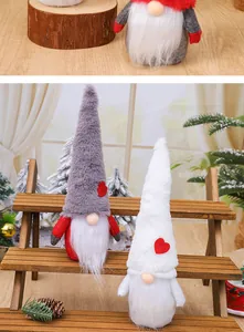 Pair of plush Christmas gnomes with heart-decorated pointy hats on a wooden display stand.