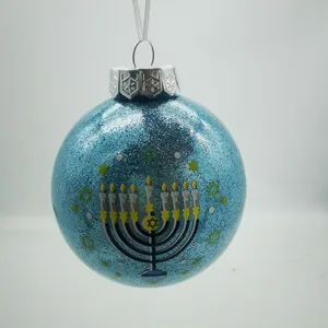 Detailaufnahme einer hellblauen Glitzer-Hanukkah-Dekokugel mit Menora- und Stern-Motiv