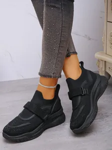 Close-up van zwarte strass sneakers met klittenband en dikke zolen op model