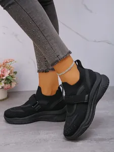 Detailopname van zwarte mesh sneakers met strass band en dikke gedempte zool.