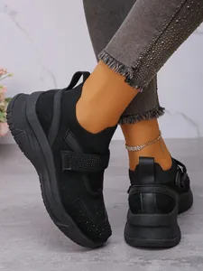 Detail van zwarte mesh sneakers met strassteentjes, dikke plateauzool en klittenband