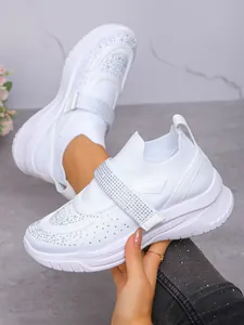 Close-up van witte ademende sneakers met sprankelende strass-steentjes en klittenband