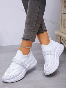Close-up van witte ademende mesh sneakers met stras klittenbandsluiting en dikke zolen