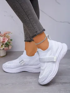 Detail van witte ademende sneakers met strass klittenbandsluiting en een dikke zool.