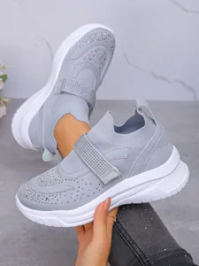 Detail van grijze mesh-sneakers met fonkelende steentjes en handige klittenbandsluiting.