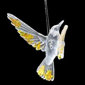Detailansicht eines transparenten Kolibri-Anhängers aus Acryl mit funkelnden goldenen Pailletten