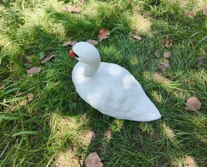 Lifelike white swan garden ornament placed on a lush green lawn for outdoor pond decoration.