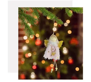Close-up of a plush pink angel girl Christmas ornament hanging on a festive tree branch.