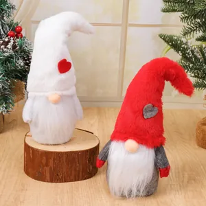 Pair of plush Christmas gnomes with tall hats and heart accents on a wooden stump