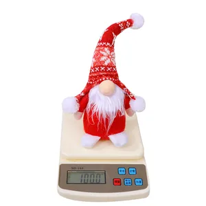 Gnomo di Natale fatto a mano con cappello rosso a maglia che pesa 100g su una bilancia