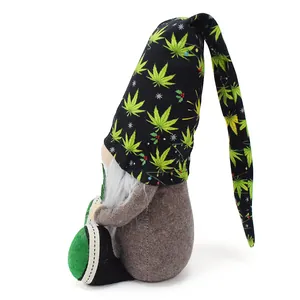 Vista di profilo di una bambola gnomo di peluche con lungo cappello nero a foglie verdi.