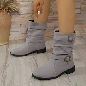 Nahaufnahme von stylischen grauen Denim-Slouch-Stiefeln mit dekorativen Bronzeschnallen
