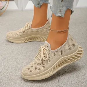 Détail de baskets en maille beige respirante aux pieds avec semelles compensées ondulées.