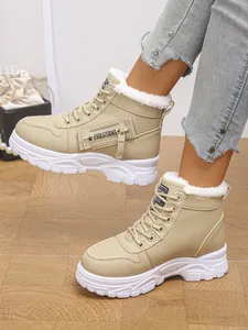 Nahaufnahme der beigen hohen Schneestiefel mit weißem Kunstfellfutter und Schnürung
