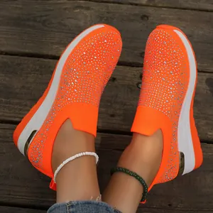 Dettaglio ravvicinato di scarpe con zeppa arancioni decorate con brillanti strass