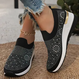 Dettaglio di sneakers nere in maglia con zeppa e decorazioni di strass brillanti