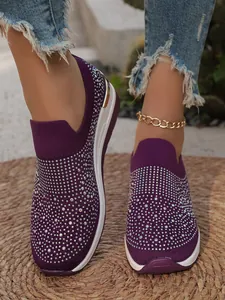 Primo piano di sneakers con zeppa in maglia viola decorate con strass per donna