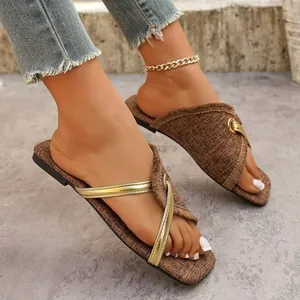 Detailansicht brauner Stoff-Sandalen mit goldenen Metallriemen und Fransenrand.
