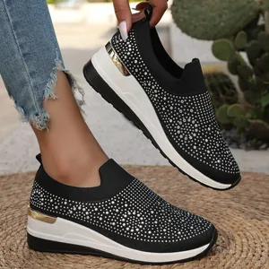Dettaglio degli strass scintillanti sulle scarpe con zeppa nere in maglia traspirante