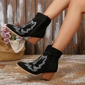 Detailed view of black western ankle boots featuring white embroidery and pointed toes.