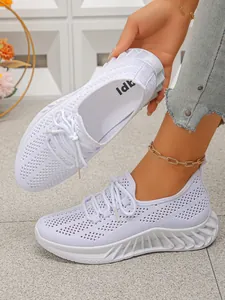 Détail de chaussures de sport blanches en maille respirante avec semelles compensées.